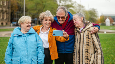 four seniors taking a selfie outdoors