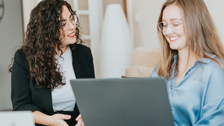 two women looking at a laptop in a work office