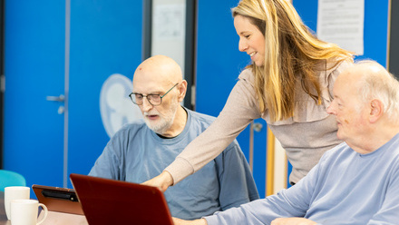 women helping man on laptop