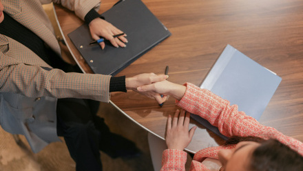 two people shaking hands over a laptop computer